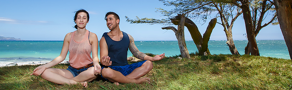 Woman and man meditating or doing yoga on a beach in Maui